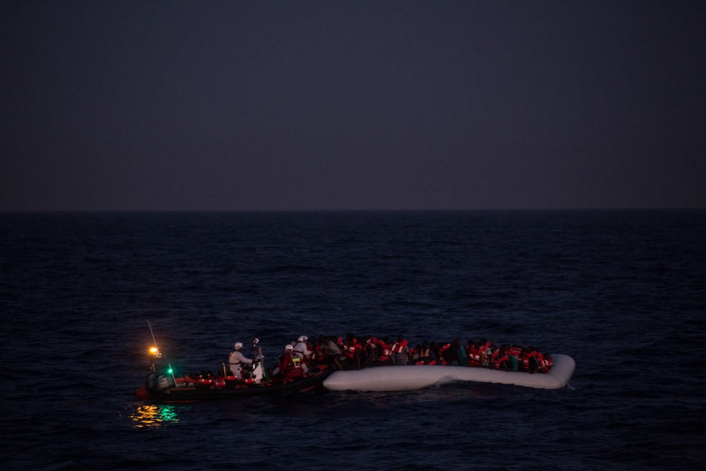 LAMPEDUSA, ITALY - JUNE 10: Refugees and migrants wait to be rescued in the early housr of the morning by crewmembers from the Migrant Offshore Aid Station (MOAS) Phoenix vessel on June 10, 2017 off Lampedusa, Italy. An estimated 230,000 refugees and migrants will arrive in Italy this year as numbers of refugees and migrants attempting the dangerous central mediterranean crossing from Libya to Italy continues to rise since the same time last year. So far this year more than 58,000 people have arrived in Italy and 1,569 people have died attempting the crossing. Libya continues to be the primary departure point for refugees and migrants taking the central mediterranean route to Sicily. In an attempt to slow the flow of migrants, Italy recently signed a deal with Libya, Chad and Niger outlining a plan to increase border controls and add new reception centers in the African nations, which are key transit points for migrants heading to Italy. MOAS is a Malta based NGO dedicated to providing professional search-and-rescue assistance to refugees and migrants in distress at sea. Since the start of the year MOAS have rescued and assisted more than 4000 people and are currently patrolling and running rescue operations in international waters off the coast of Libya. (Photo by Chris McGrath/Getty Images)